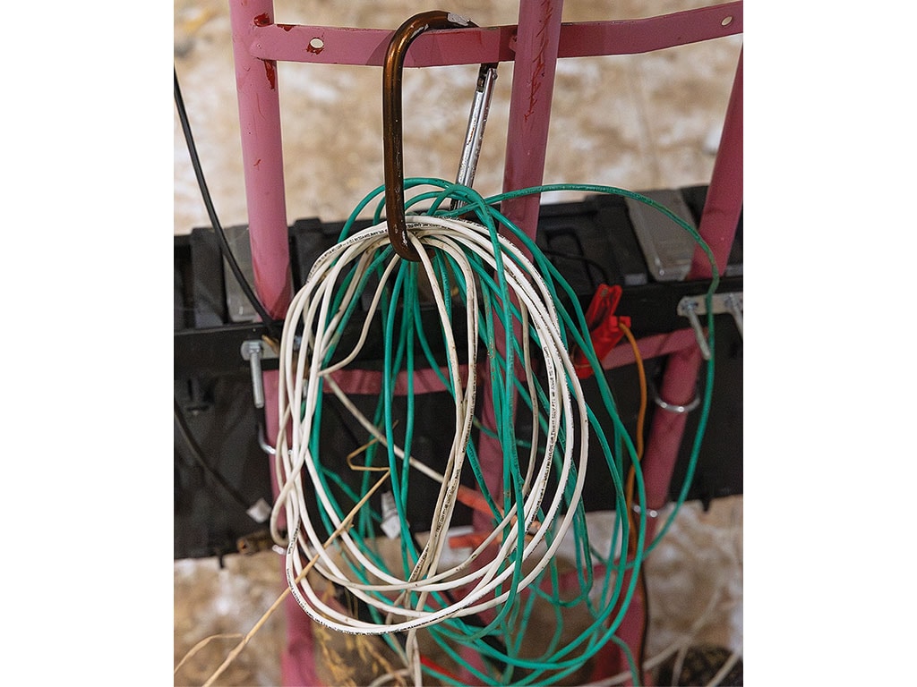 Electrical wires coiled on a metal hook attached to a ladder