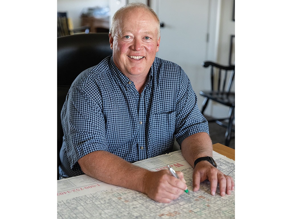 Person in a checkered shirt sitting at a table with a map and pen.