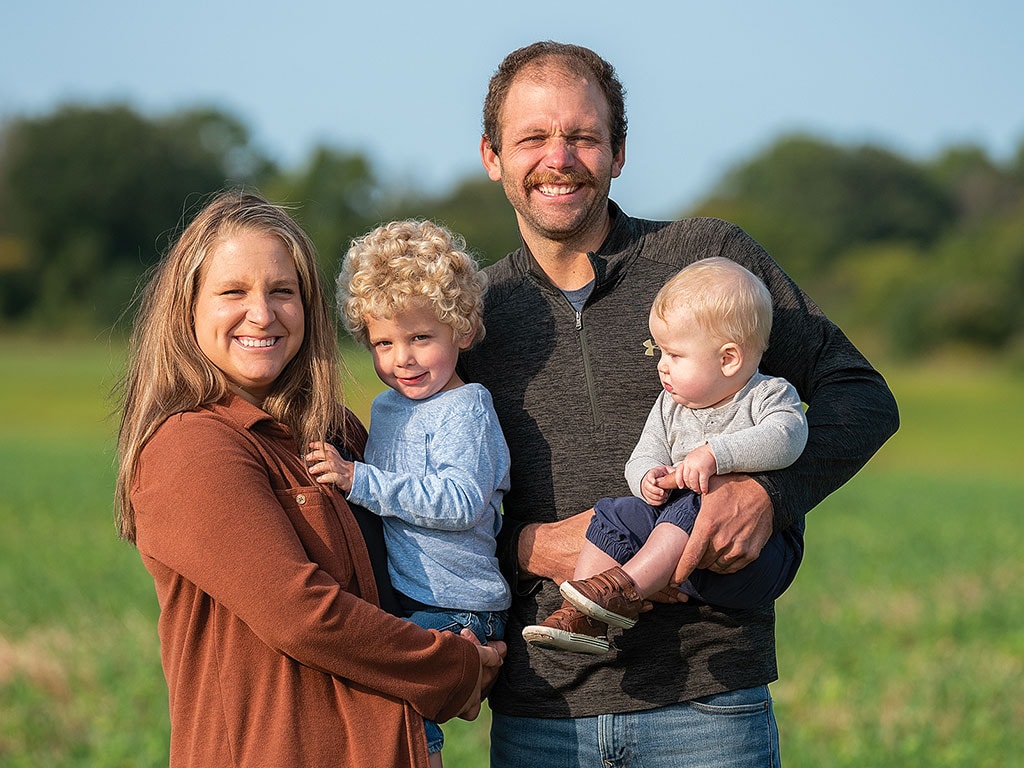 A family standing in a field smiling.