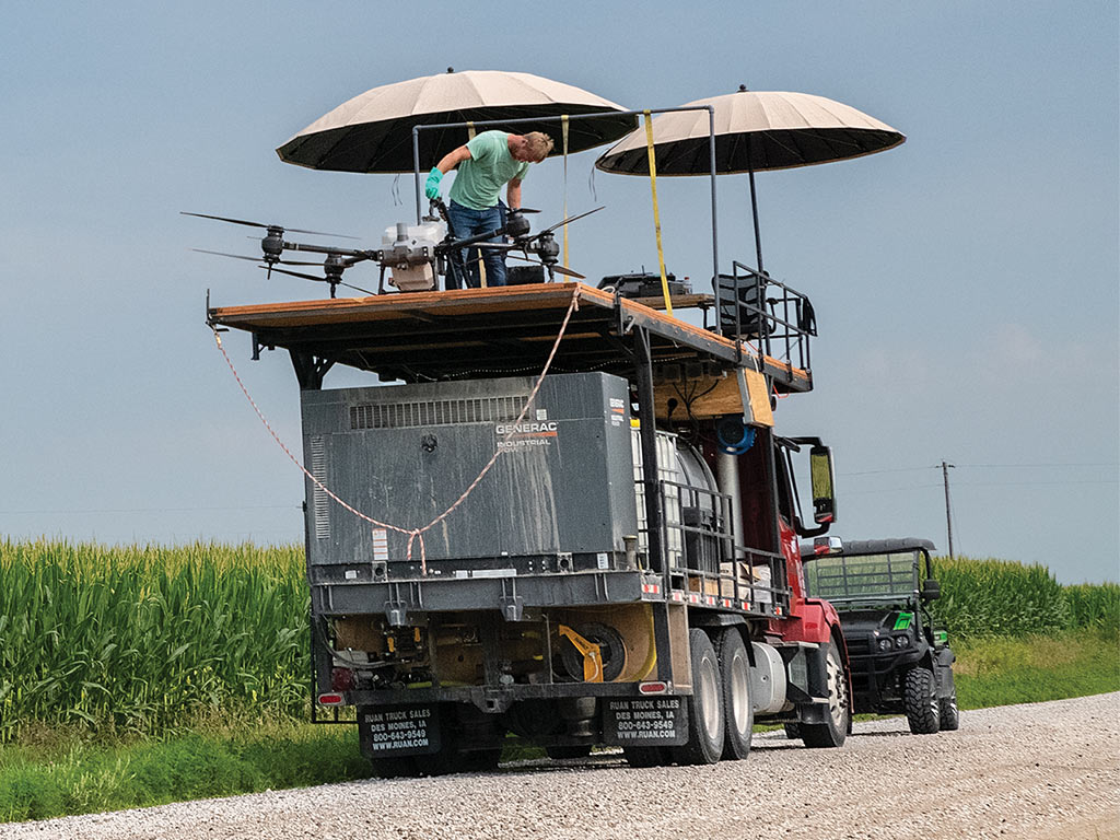 A tender truck and plaform with umbrellas, a worker checking over drones.