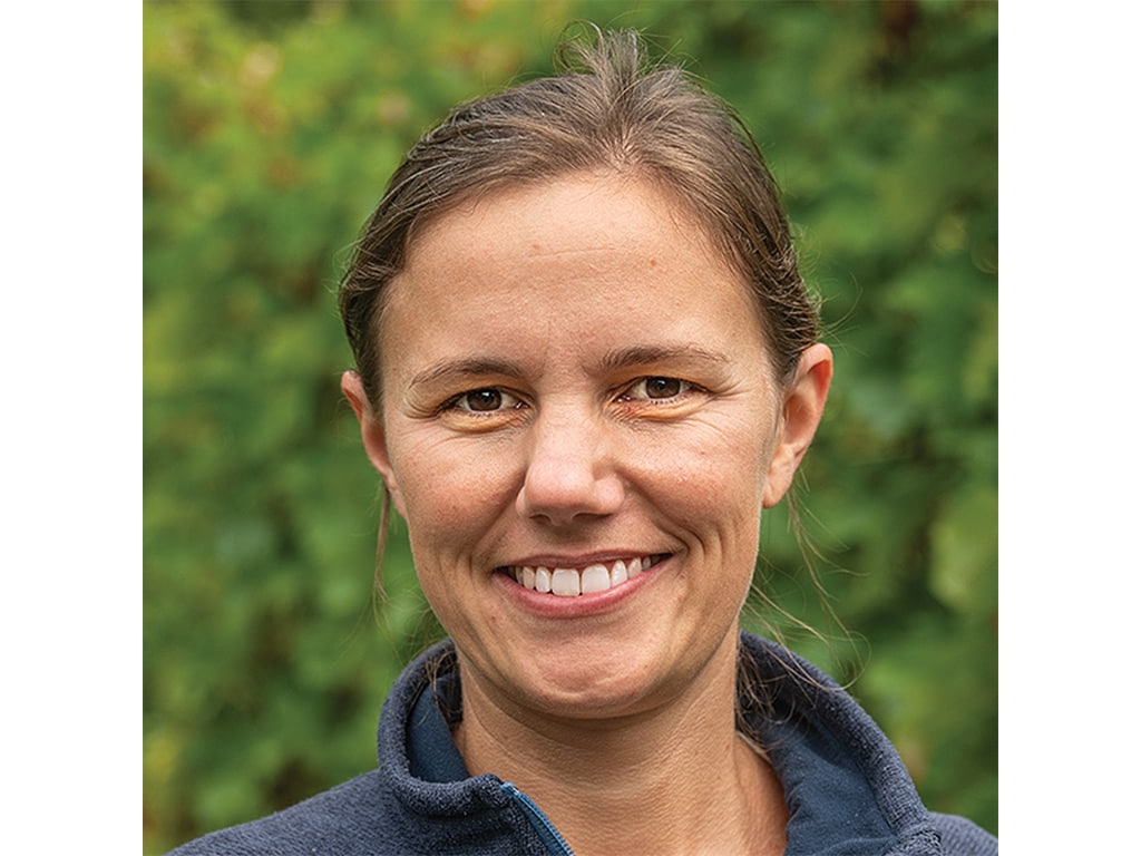 A woman with brown hair, wearing a navy blue jacket.