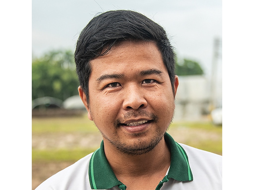 A man stands outdoors wearing a green-collared shirt.