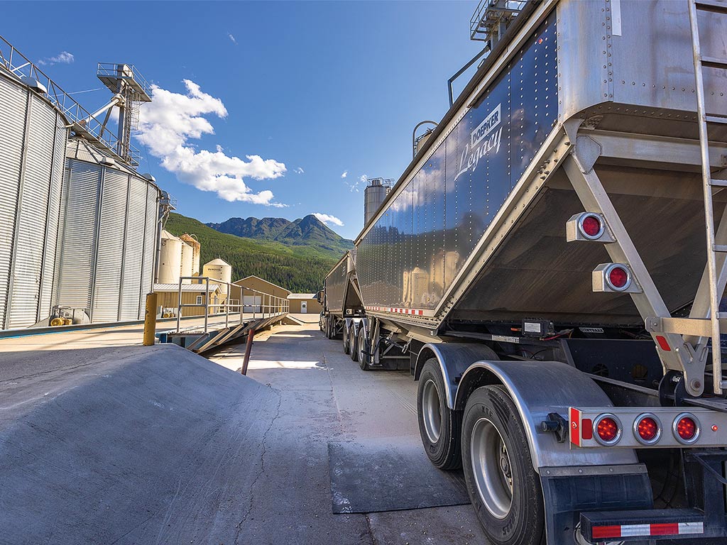 A line of parked steel semi trailers and silos