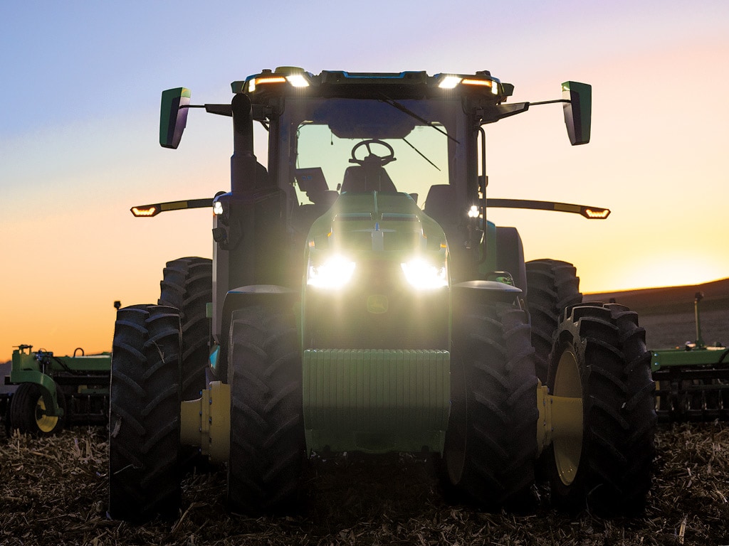 A driverless tractor tilling a field at dusk or dawn 